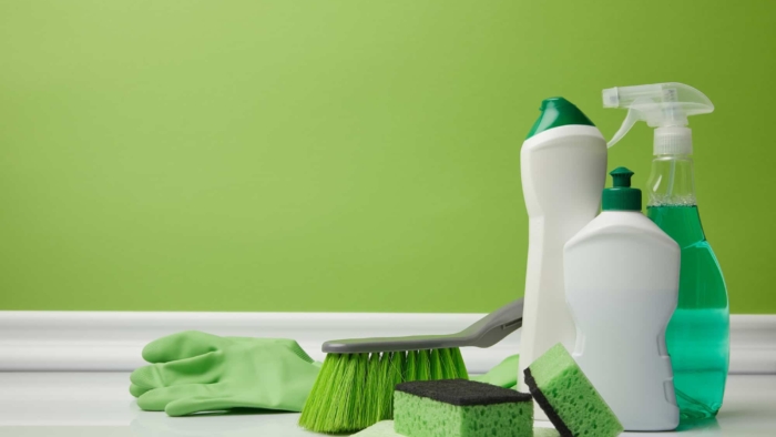 cleaning-bottles-and-supplies-against-green-background